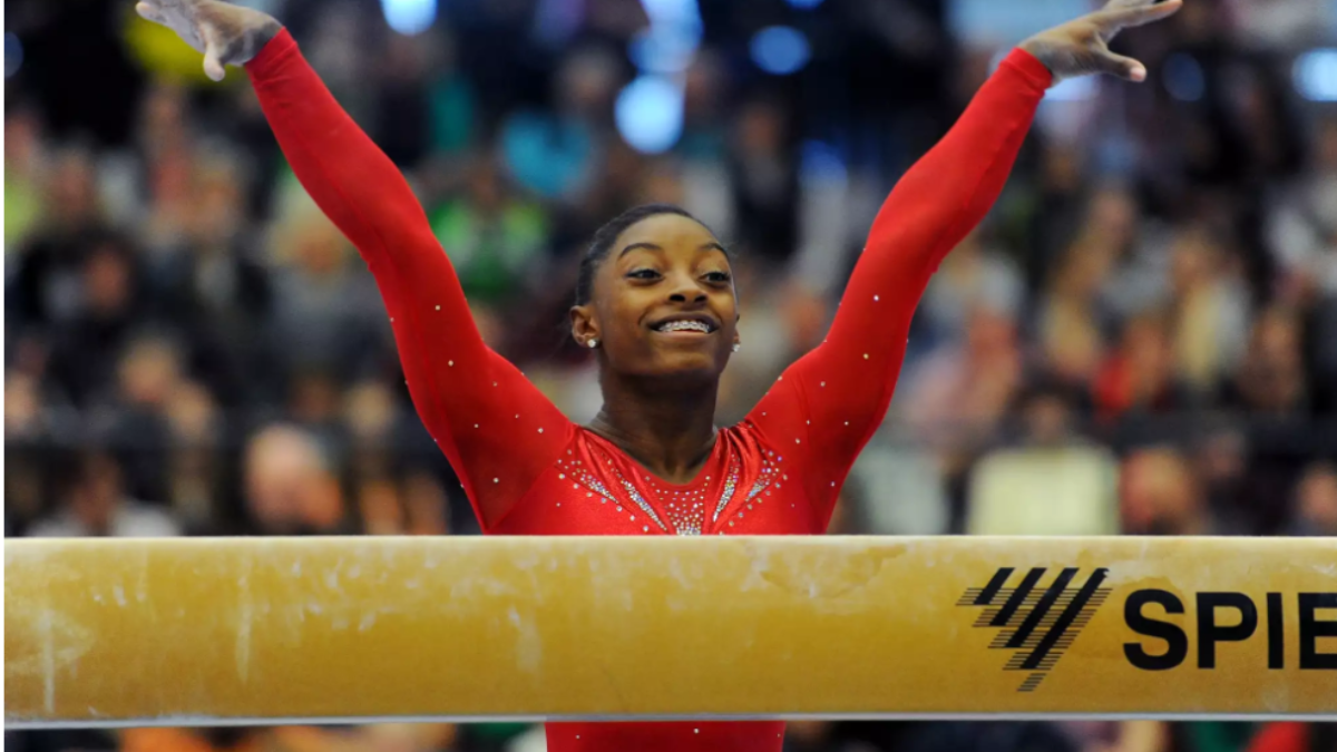 Simon Biles' performing a gymnastic routine showcasing her skills and athleticism.